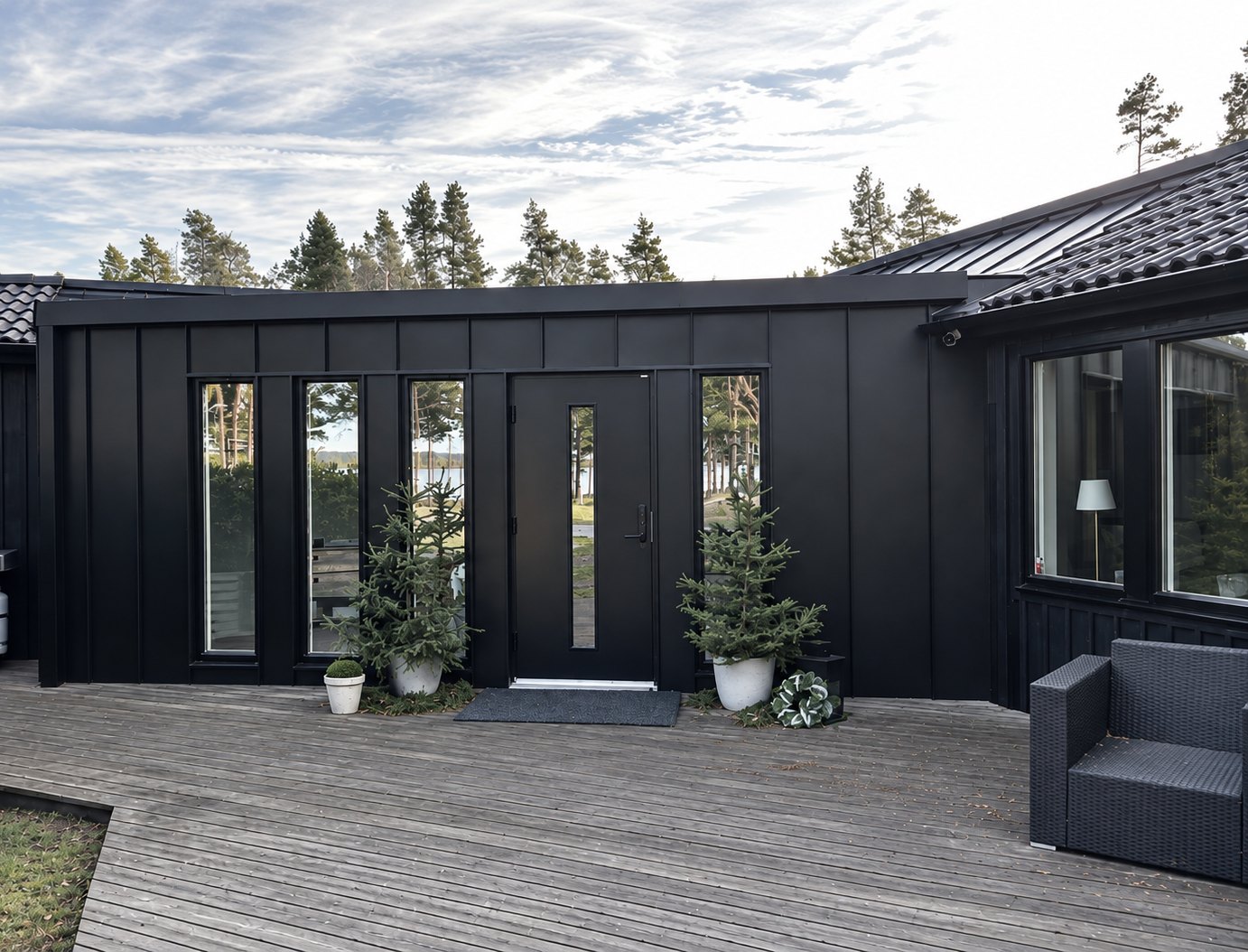 Svart fasadplåt med stående falsar och plåttak på ett hus vid vattnet på Oknö i Mönsterås