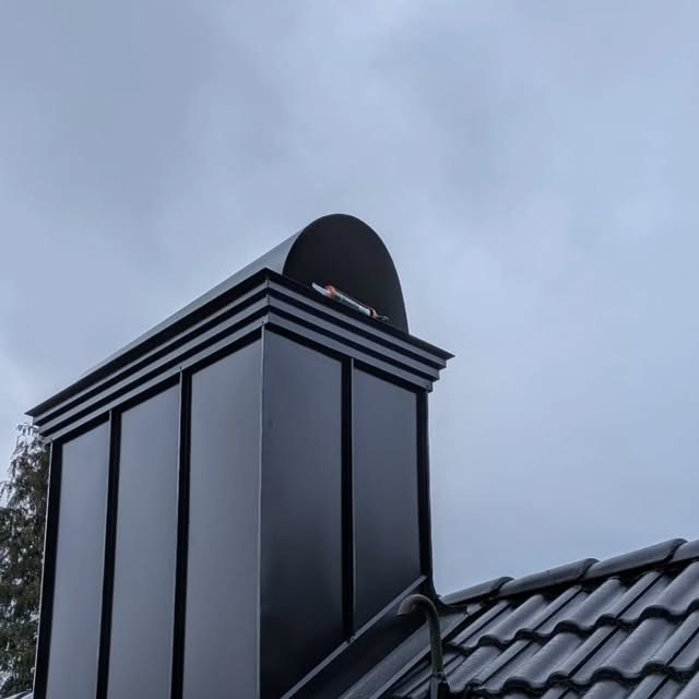 Svart skorstensinklädnad i plåt med skorstenskrona och båge
